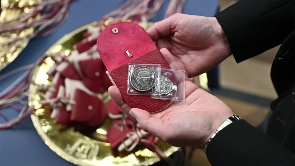 Red purses which contain a £5 coin which Queen Camilla has distributed