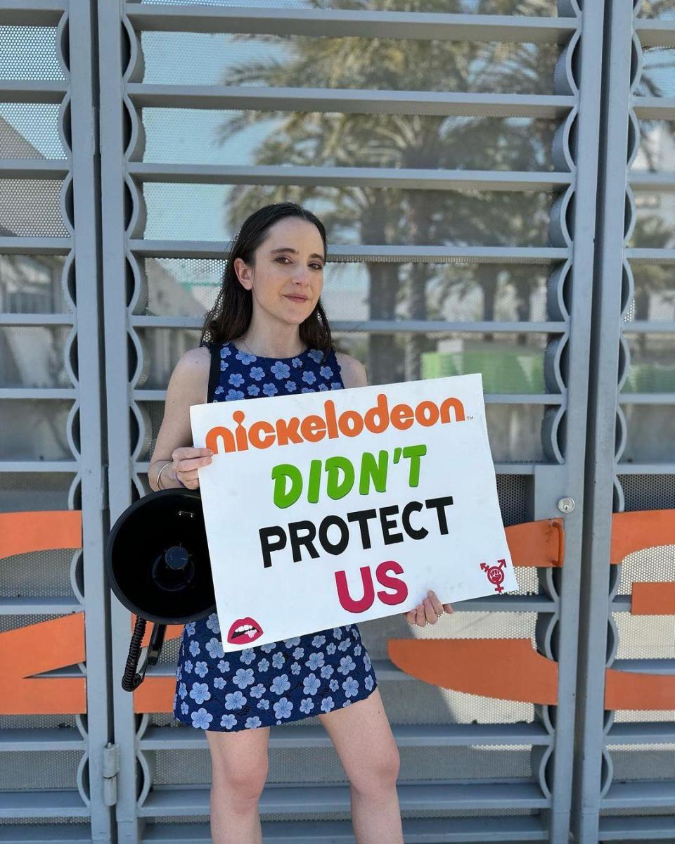 Alexa Nikolas holding 'Nickelodeon Didn't Protect Us' sign