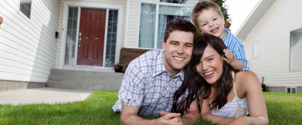 Portrait of happy family lying down on grass in front of house