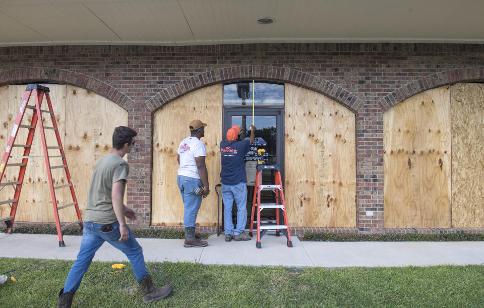 Bernie Arnould, center, gets help from Kaden Ashley and D.J. Hebert, left, all with Pelican Companies, as they board up the windows to the front of MC Bank in Amelia, La., Wednesday, Oct., 7, 2020, in In preparation for Hurricane Delta. (Chris Granger/The Times-Picayune/The New Orleans Advocate via AP)