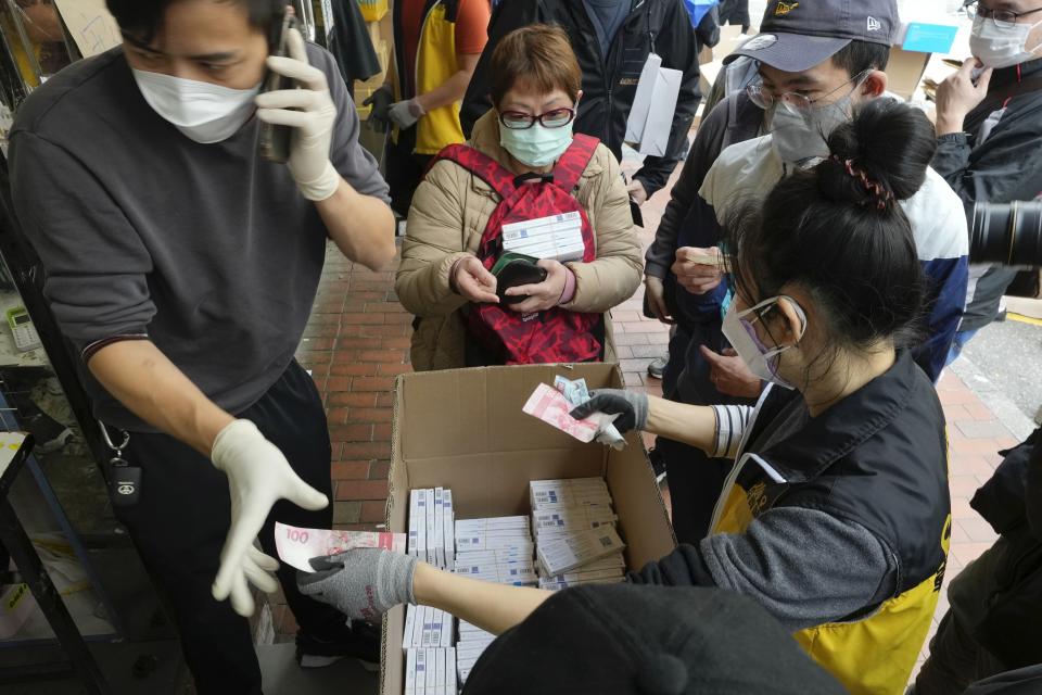 Customers wearing face masks purchase COVID-19 antigen test kits at a market in Hong Kong, Monday, Feb. 28, 2022. (AP Photo/Vincent Yu)