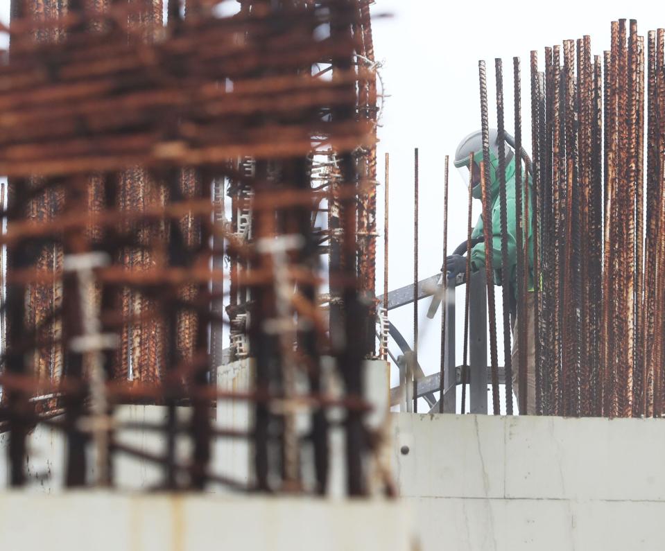 A worker on Tuesday sandblasts rust off of the rebar of the oceanside condo project being developed by Protogroup.