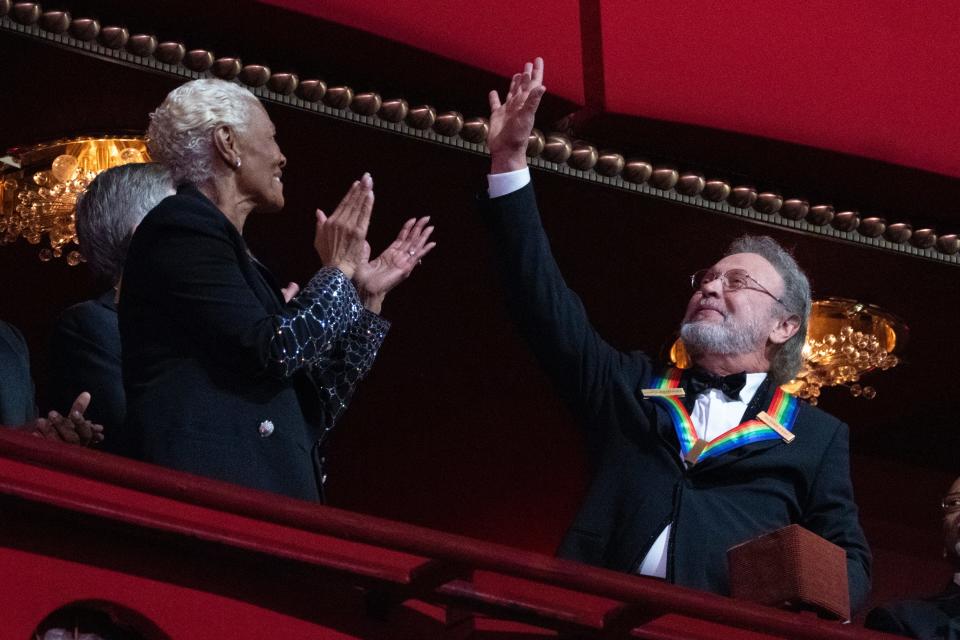 2023 Kennedy Center Honoree Billy Crystal waves as he is applauded by fellow honoree Dionne Warwick at the 46th Kennedy Center Honors at the John F. Kennedy Center for the Performing Arts in Washington, Sunday, Dec. 3, 2023.