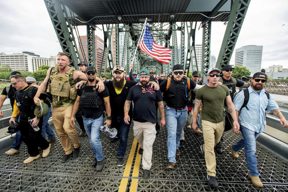 Members of the Proud Boys and other right-wing demonstrators march across the Hawthorne Bridge during an &quot;End Domestic Terrorism&quot; rally in Portland, Ore., on Saturday, Aug. 17, 2019. The group includes organizer Joe Biggs, center in green hat, and Proud Boys Chairman Enrique Tarrio, holding megaphone. (AP Photo/Noah Berger)