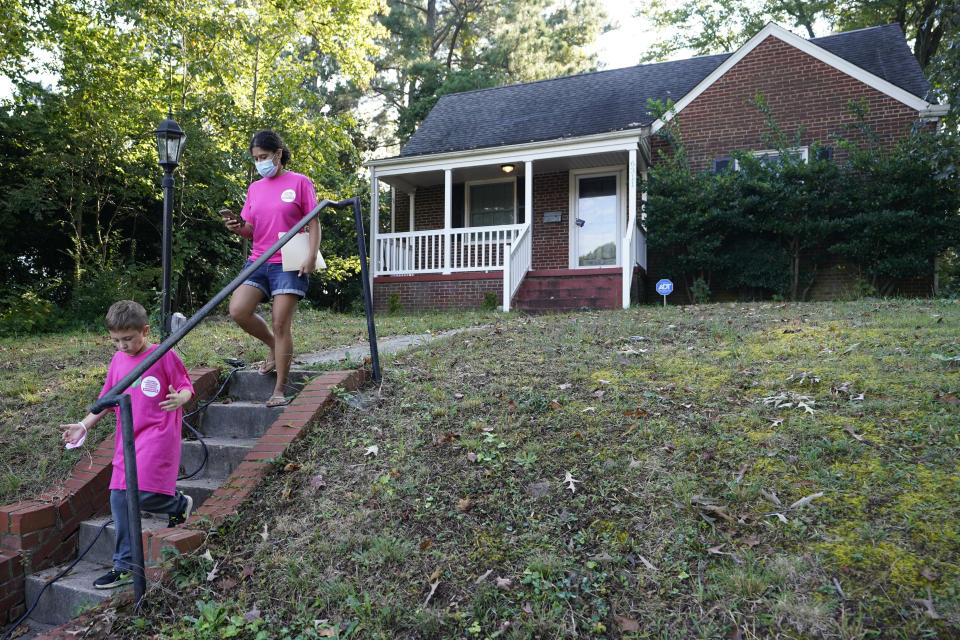 In this Saturday, Oct. 16, 2021, photo Han Jones, of Planned Parenthood Advocates of Virginia, right, and Henry Pickett, leave a house after leaving literature while canvassing the area to encourage voters to vote in Richmond, Va. (AP Photo/Steve Helber)