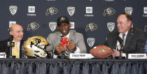 Deion Sanders, center, uses his mobile telephone to illustrate how Rick George, right, Colorado athletic director, kept in touch while courting Sanders to become the new head football coach at Colorado during a news conference Sunday, Dec. 4, 2022, in Boulder, Colo. Colorado chancellor Phil DeStefano, left, looks on. Sanders left Jackson State University after three seasons at the helm of the school's football team. (AP Photo/David Zalubowski)