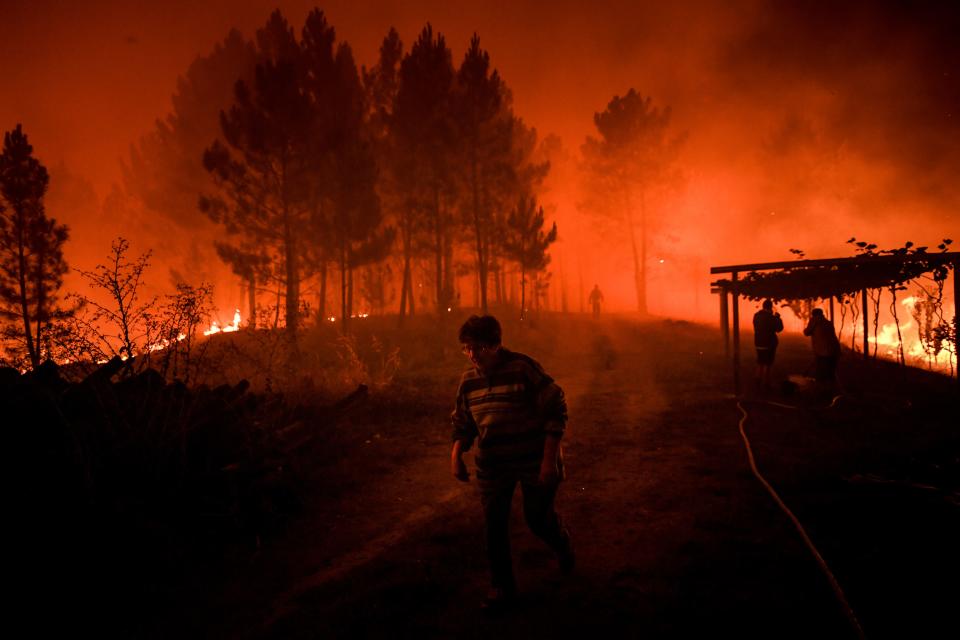 A villager walks past a wildfire encroaching on her home in Amendoa in Macao, central Portugal on July 21, 2019. (Photo: Patricia De Melo Moreira/AFP/Getty Images)