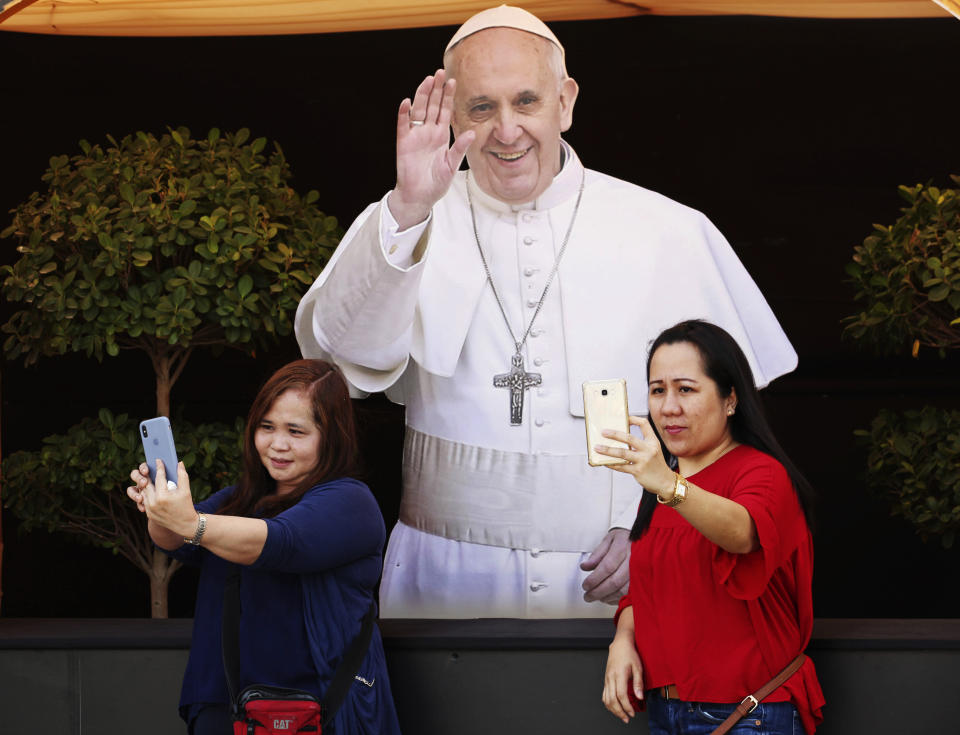 In this Sunday, Jan. 20, 2019 photo, two parishioners at St. Mary's Catholic Church take photographs of themselves in front of a cut-out picture of Pope Francis, in Dubai, United Arab Emirates. The pontiff’s visit from Feb. 3 through Feb. 5 marks the first papal visit in history to the Arabian Peninsula, the birthplace of Islam. There are nine Catholic churches in the federation of seven sheikhdoms governed by hereditary rulers. (AP Photo/Jon Gambrell)