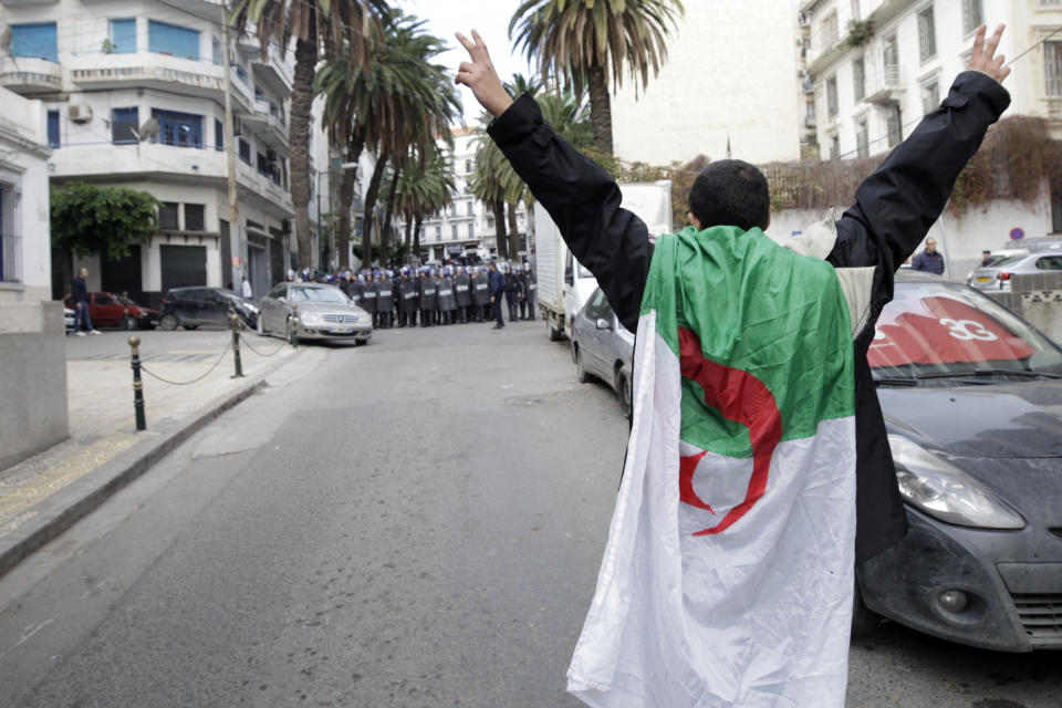 An Algerian demonstrator gestures towards security forces as people take to the streets in the capital Algiers to reject the presidential elections, in Algeria, Thursday, Dec. 12, 2019. Five candidates have their eyes on becoming the next president of Algeria _ without a leader since April _ in Thursday's contentious election boycotted by a massive pro-democracy movement. (AP Photo)