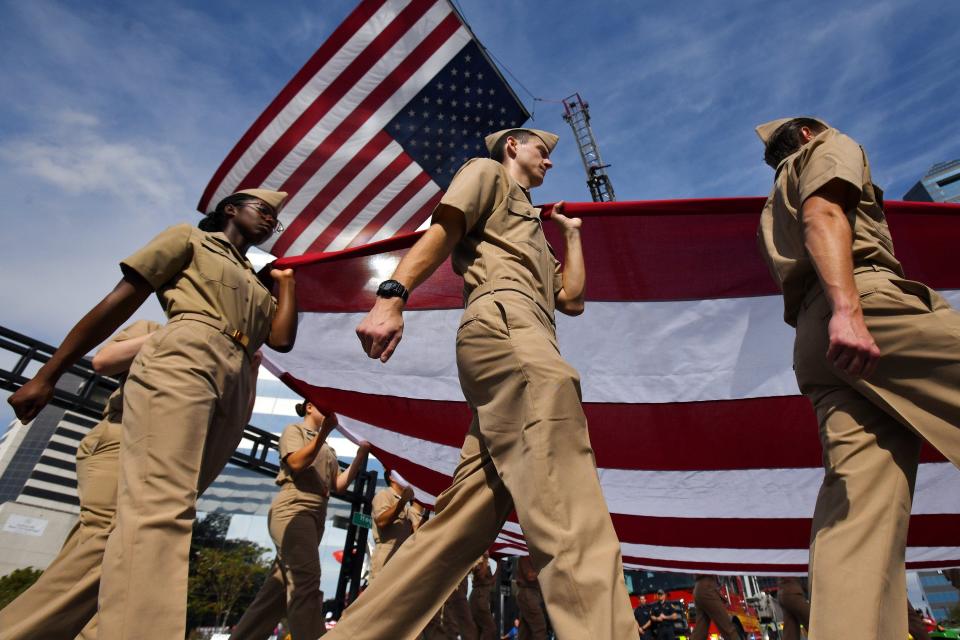 On the 2021 Veterans Day parade route, members of the Jacksonville University NROTC program carry an oversized American flag under an even larger one hung between two fire trucks. A new survey aims to find out the needs of Northeast Florida veterans.