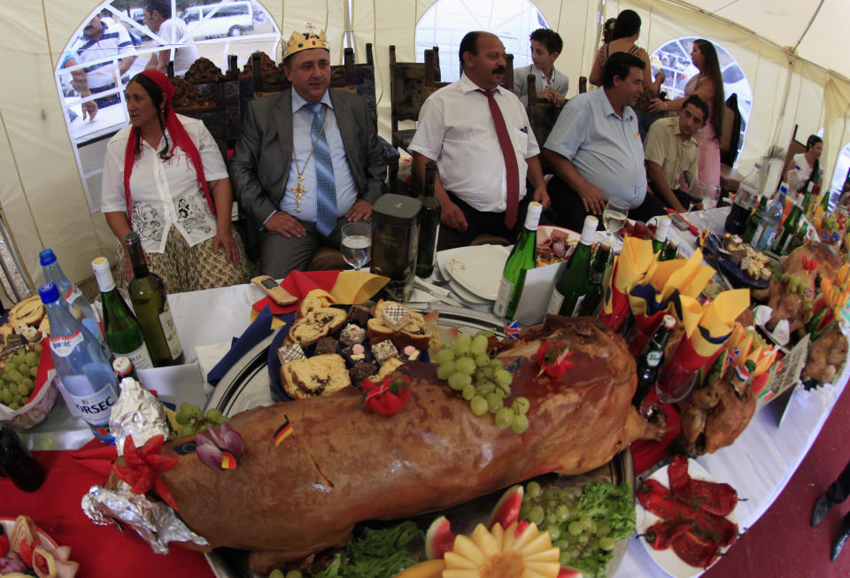 Self proclaimed international king of gypsies Stanescu sits among relatives at a table with a roasted pig on display during the traditional ethnic Roma festival in Costesti