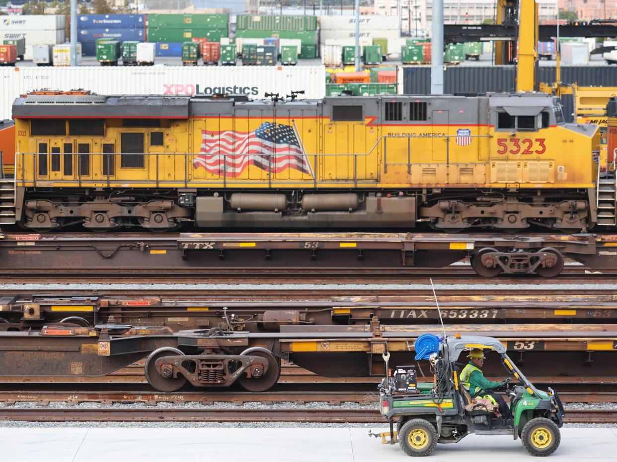 A worker drives near freight trains and shipping containers in a Union Pacific Intermodal Terminal rail yard on November 21, 2022 in Los Angeles, California.