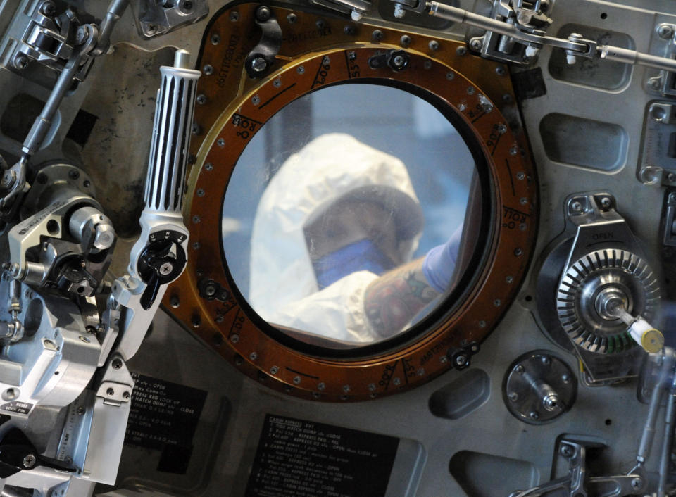 Gary Phillips is shown through a hatch window cleaning the exterior of the Apollo 16 spacecraft at the U.S. Space and Rocket Center in Huntsville, Ala., on Tuesday, Feb. 1, 2022. Following a break in routine maintenance because of the COVID-19 pandemic, the museum is sprucing up the antique spaceship before events marking the 50th anniversary of its flight in 1972. (AP Photo/Jay Reeves)