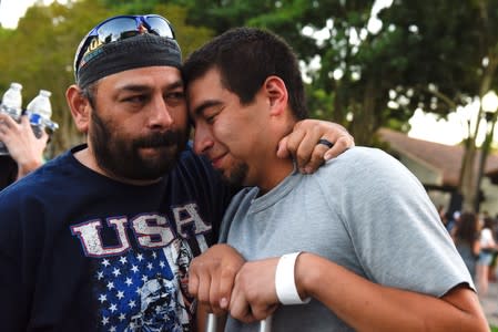 Justin Bates (R), a survivor of the Gilroy Garlic Festival mass shooting, is comforted by his father, Rob Bates, during a vigil outside of Gilroy City Hall