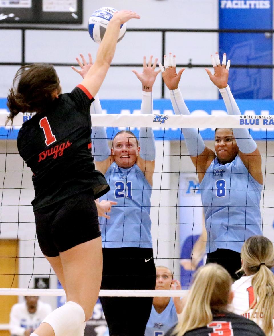 Western outside hitter Paige Briggs (1) hits the ball over the net as Middle Tennessee setter Taylor Eisert (21) and Middle Tennessee middle blocker Dasia Smith (8) defend the net during a volleyball match at MTSU on Thursday, Nov 9, 2023.