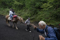 Two climbers on a horse descend the Yoshida trail of Mount Fuji as one goes up Monday, Aug. 26, 2019, in Japan. (AP Photo/Jae C. Hong)