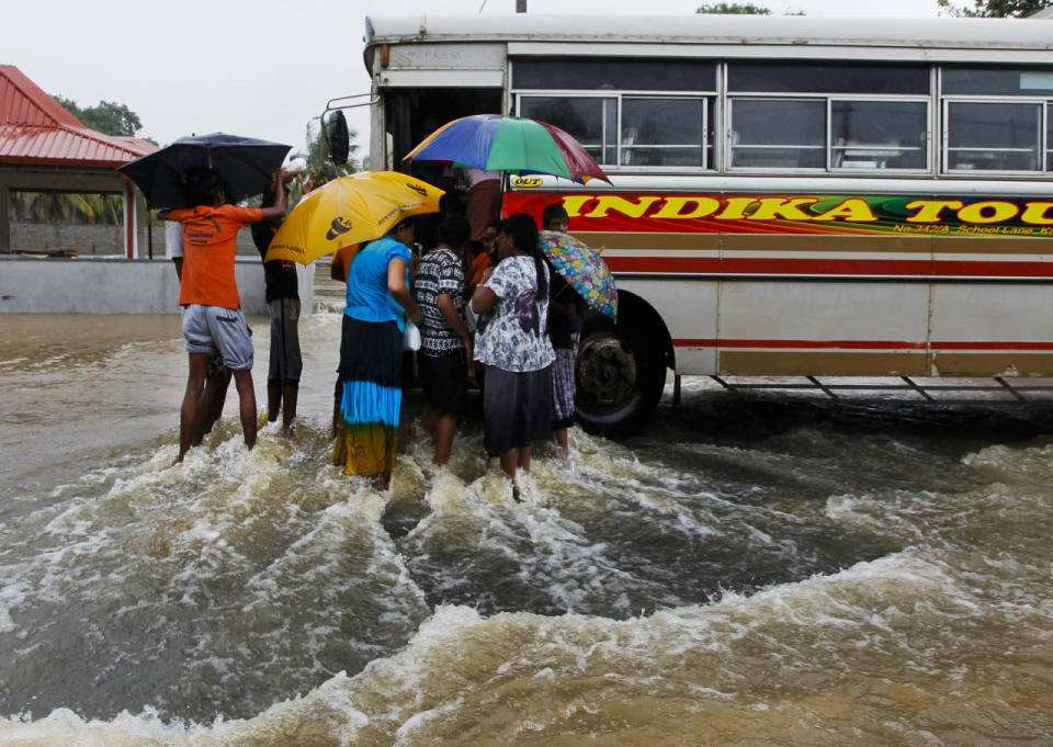 Flood victims flock around a bus to receive food parcels on an inundated road in Colombo, Sri Lanka, May 17, 2016. (AP Photo/Eranga Jayawardena)