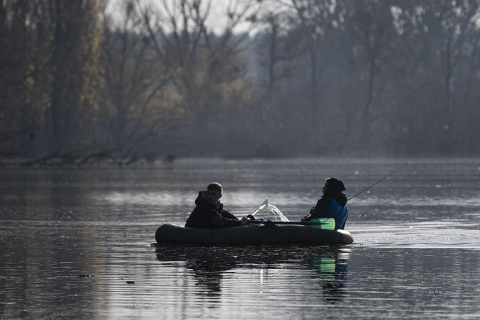 People fish in a flooded area in the village of Demydiv, about 40 kilometers (24 miles) north of Kyiv, Ukraine, Tuesday, Nov. 2, 2022. After the flood in Demydiv, residents said their tap water turned cloudy, tasted funny and left a film on pots and pans after cooking. The village was under Moscow's control until April, when Russian troops withdrew after failing to take the capital. (AP Photo/Andrew Kravchenko)