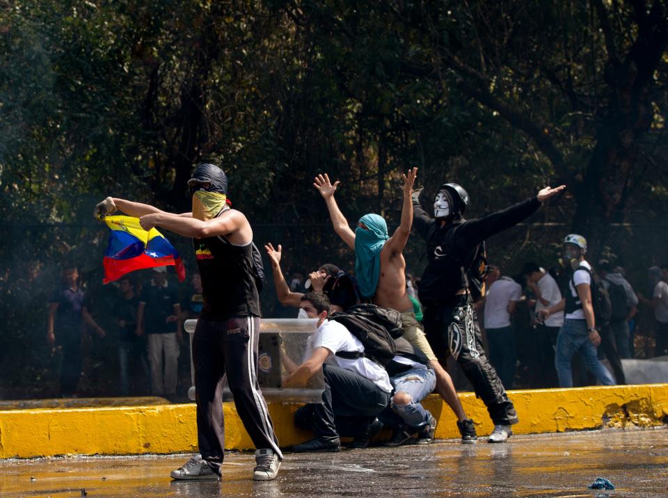 Demonstrators shout insults at Bolivarian National Police officers during clashes at an anti-government protest in Caracas, Venezuela, Wednesday, March 12, 2014. A university student has died and a number of others, including three National Guardsmen, have been wounded after being shot by unknown assailants in two separate incidents in the central Venezuelan city of Valencia. (AP Photo/Fernando Llano)