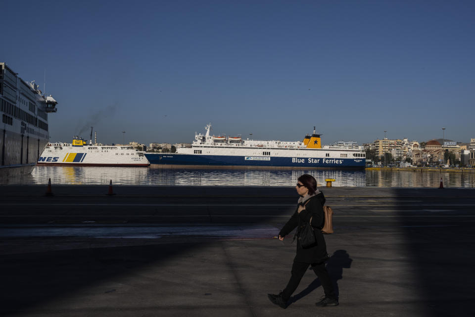 Una mujer pasa por delante de transbordadores atracados durante una huelga de 24 horas, en el puerto de Pireo, cerca de Atenas, el 8 de marzo de 2023. (AP Foto/Petros Giannakouris)