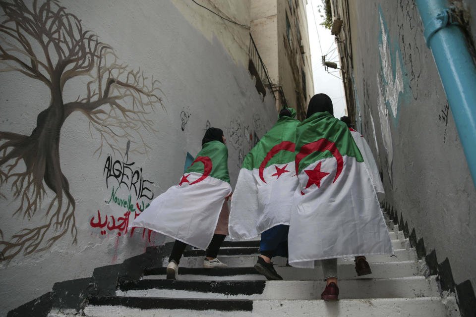 Female protesters wrapped in Algerian flags walk past during a demonstration in Algiers, Algeria, Wednesday, April 10, 2019. The Algerian senator Abdelkader Bensalah named to temporarily fill the office vacated by former President Abdelaziz Bouteflika said he would act quickly to arrange an "honest and transparent" election to usher in an "Algeria of the future." (AP Photo/Mosa'ab Elshamy)