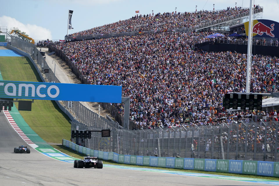 Fans watch as cars approach turn one during the F1 U.S. Grand Prix auto race at Circuit of the Americas, Sunday, Oct. 24, 2021, in Austin, Texas. (AP Photo/Darron Cummings, Pool)