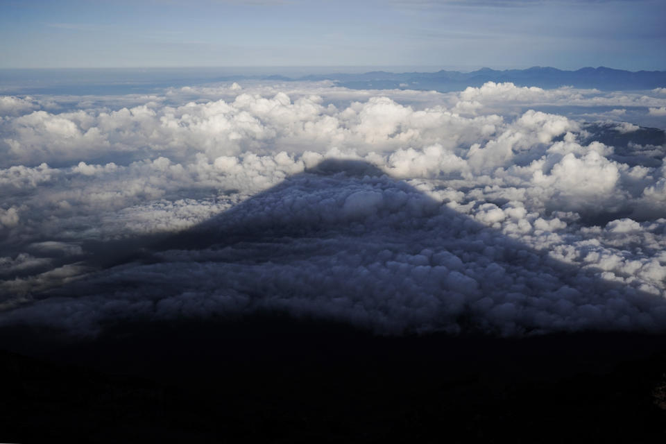 The shadow of Mount Fuji is casted on clouds hanging below the summit, Tuesday, Aug. 27, 2019, in Japan. (AP Photo/Jae C. Hong)