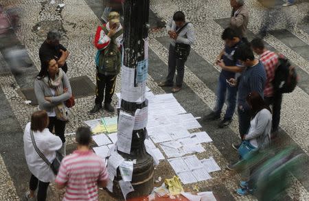 People look at a list of job offers posted in a main street in downtown Sao Paulo August 13, 2014. REUTERS/Paulo Whitaker