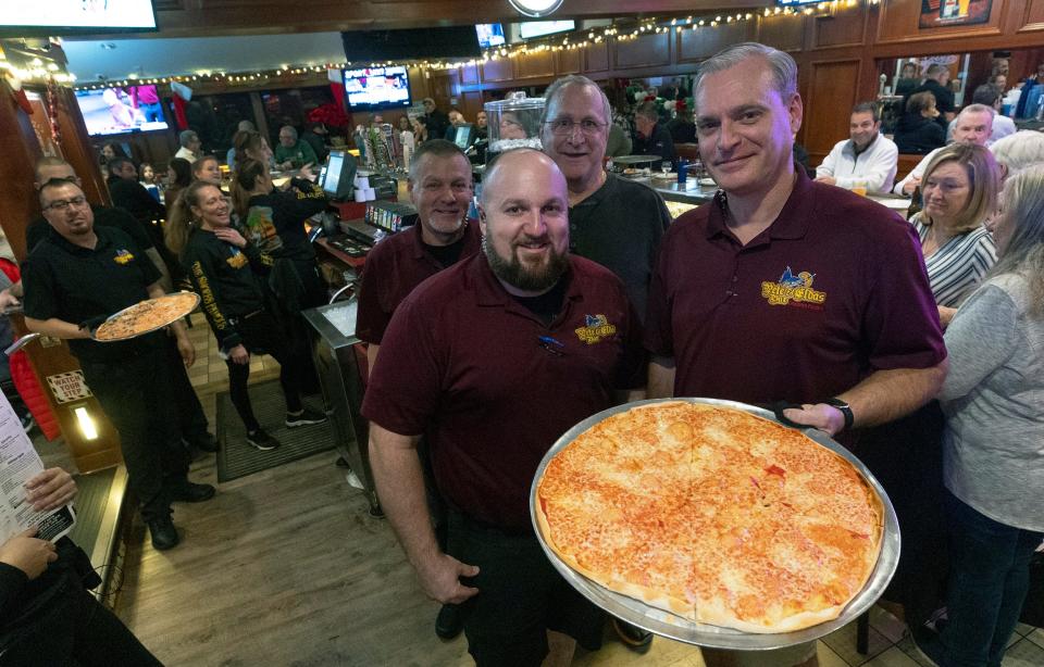 Pete and Elda's Bar owners George and Chris Andretta with their staff, who serve up Carmen's Pizza. The eatery's pizza challenge has been going for 30 years and has become a local phenomenon.