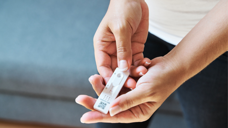 Close image of woman holding rapid antigen test in her hands.