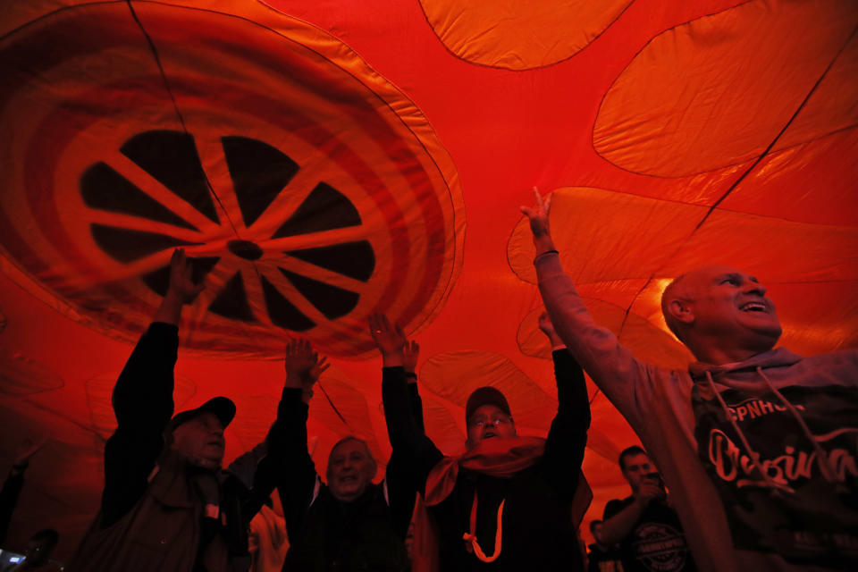 Supporters of a movement for voters to boycott the referendum, hold a huge Macedonian flag as they celebrate in central Skopje, Macedonia, after election officials gave low turnout figures, Sunday, Sept. 30, 2018. The crucial referendum on accepting a deal with Greece to change the country's name to North Macedonia to pave the way for NATO membership attracted tepid voter participation Sunday, a blow to Prime Minister Zoran Zaev's hopes for a strong message of support. (AP Photo/Thanassis Stavrakis)