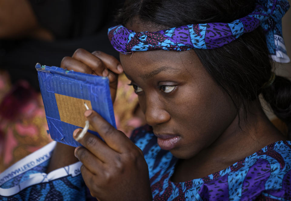 In this photo taken Monday, Feb. 18, 2019, a dancer checks her make-up before performing in a music video calling for a peaceful election, at a golf resort outside of Kano, northern Nigeria. Faced with an election that could spiral into violence, some in the popular Hausa-language film industry known as Kannywood assembled this week to shoot an urgent music video appealing to the country for peace. (AP Photo/Ben Curtis)