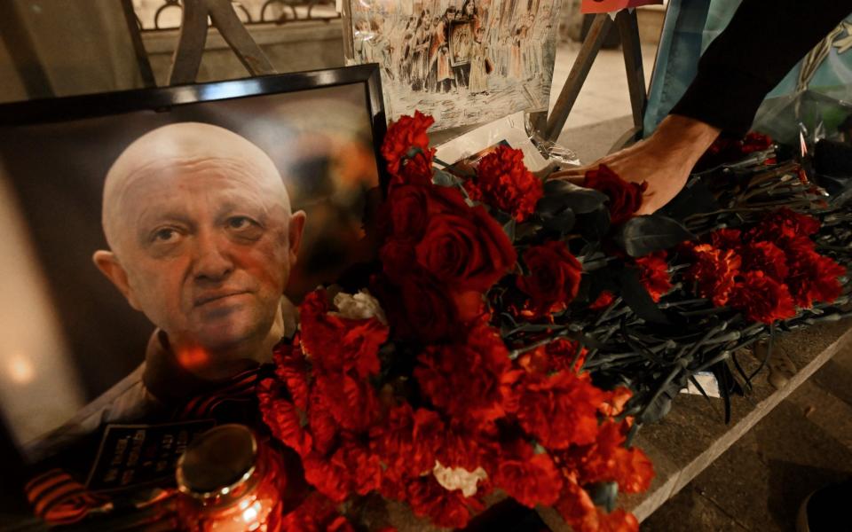 A man lays flowers at the makeshift memorial in honor of Yevgeny Prigozhin and Dmitry Utkin