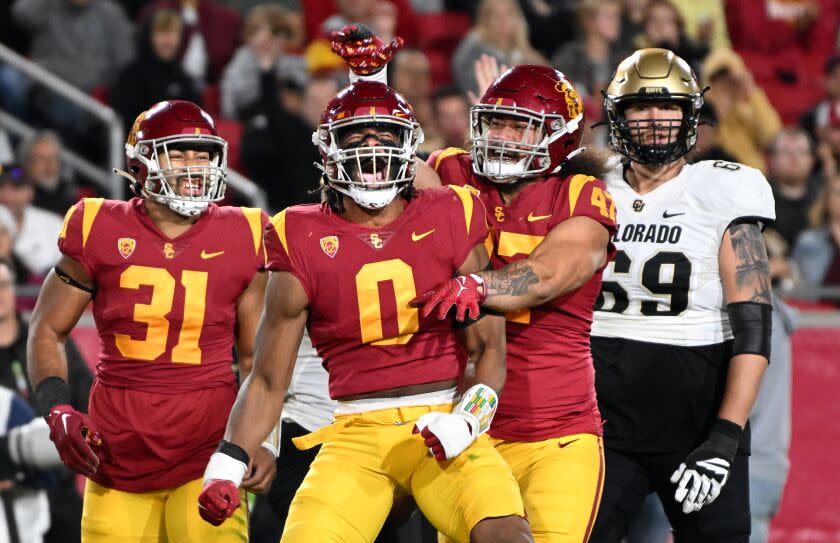 Los Angeles, California November 11, 2022- USC's Korey Foreman (0) celibrates his tackle for a loss with Tyrone Talent (31) and Stanley Taufo'ou against Colorado in the second quarter at the Coliseum Friday. (Wally Skalij/Los Angeles Times)