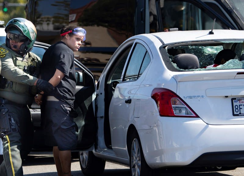 An unidentified woman is taken into custody after witnesses said she drove her car into a crowd of protesters in Yorba Linda, Calif., Saturday, Sept. 26, 2020. (Mindy Schauer/The Orange County Register via AP)