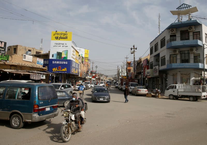 A man with a face mask rides a motorbike in Falluja