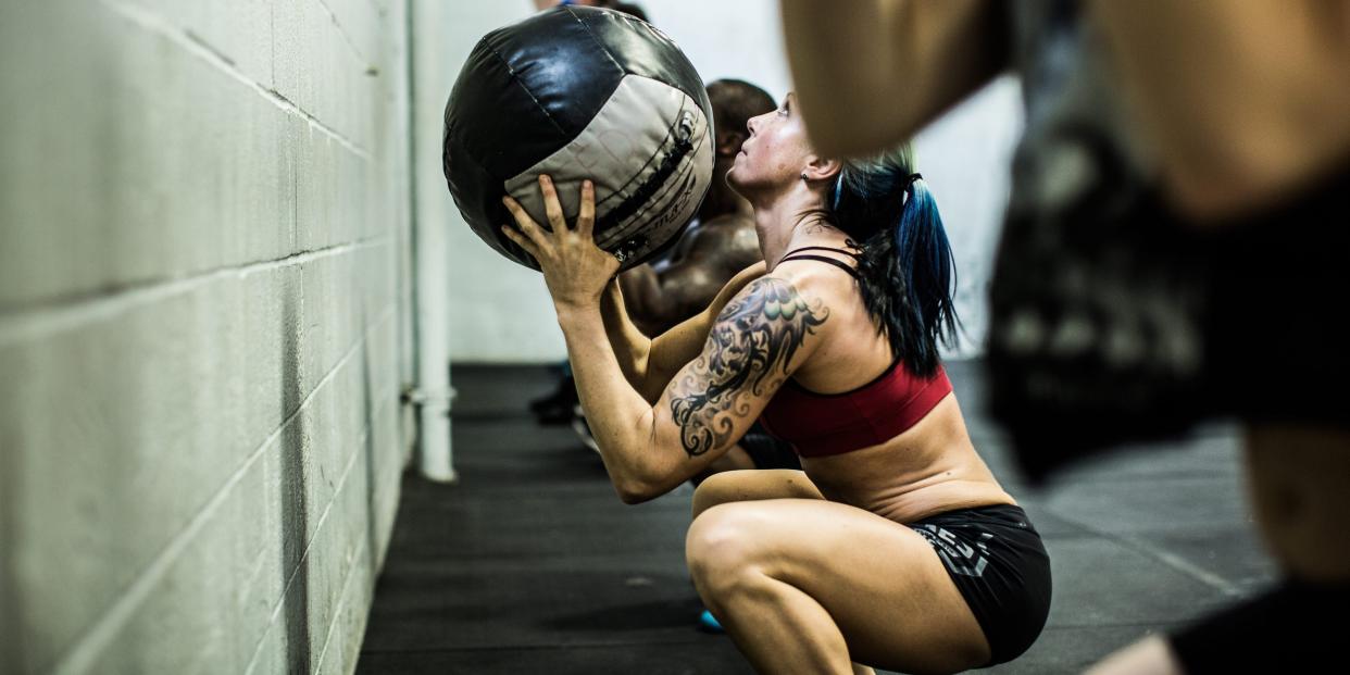 Person crouching and holding a wall ball, about to throw it against a wall.