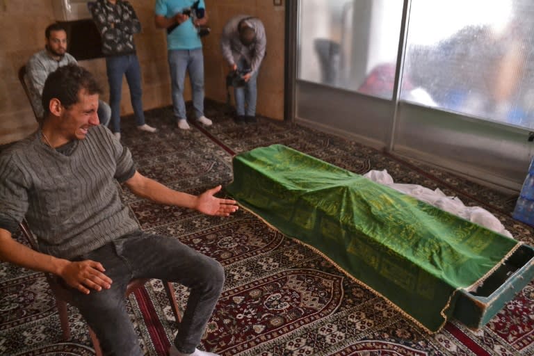 Un hombre llora ante el cadáver, cubierto por una tela verde, de una persona fallecida en el naufragio de un bote lleno de migrantes en la costa de Trípoli, el 25 de abril de 2022 durante su funeral en esa ciudad al norte de Líbano (AFP/Fathi al Masri)