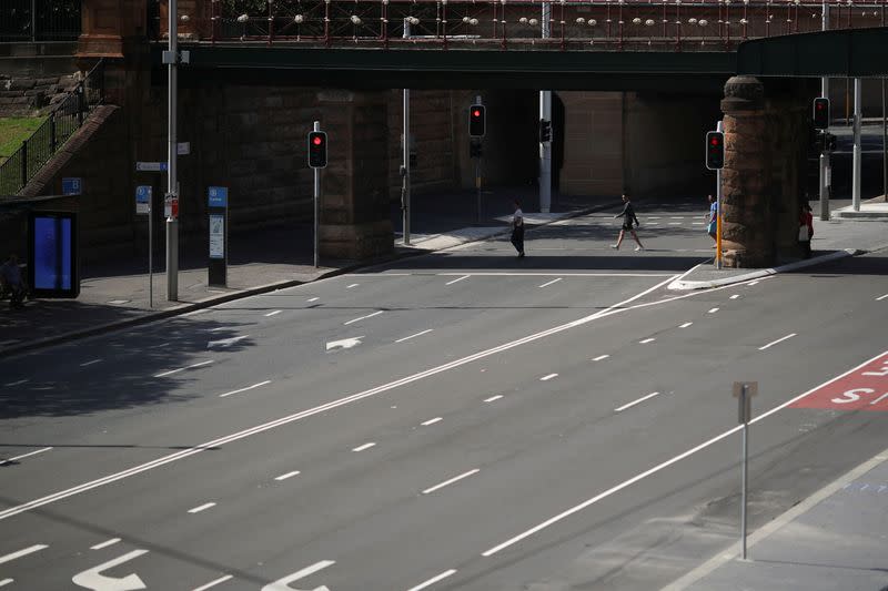 People walk by an almost empty street during a workday following the implementation of stricter social-distancing and self-isolation rules to limit the spread of the coronavirus disease (COVID-19) in Sydney