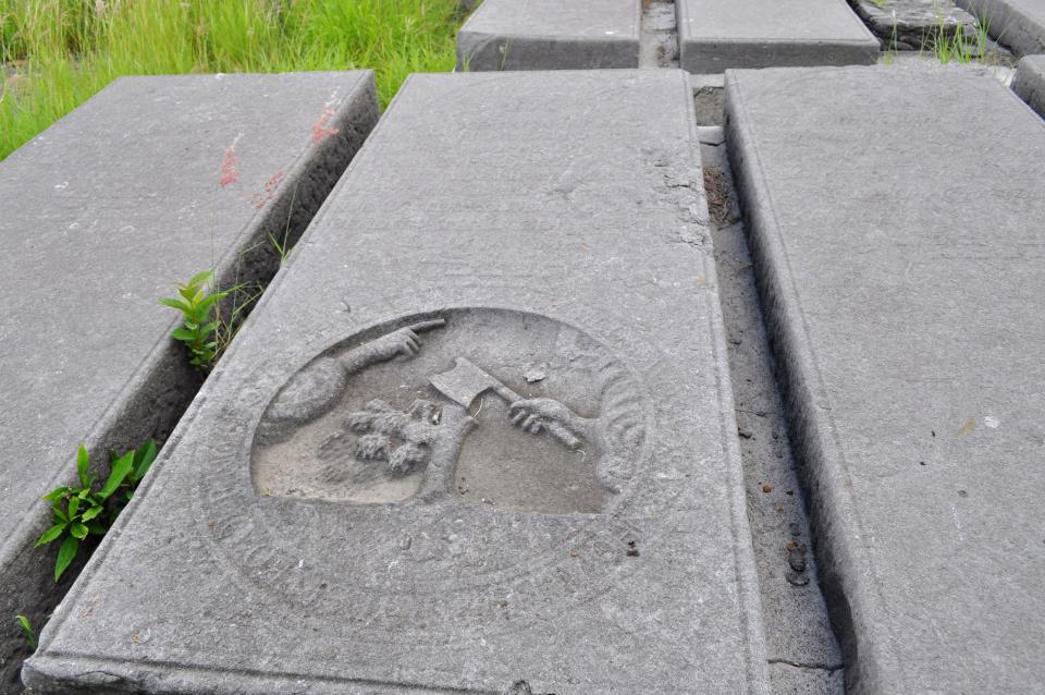 In this Nov. 12, 2012 photo, a tombstone lays in the Beth Haim cemetery in Blenheim on the outskirts of Willemstad, Curacao. Beth Haim, believed to be one of the oldest Jewish cemeteries in the Western Hemisphere, established in the 1950s and considered an important landmark on an island where the historic downtown has been designated a UNESCO World Heritage Site, is slowly fading in the Caribbean sun. Headstones are pockmarked with their inscriptions faded, stone slabs that have covered tombs in some cases for hundreds of years are crumbling into the soil, marble that was once white is now grey, likely from the acrid smoke that spews from the oil refinery that looms nearby. (AP Photo/Karen Attiah)