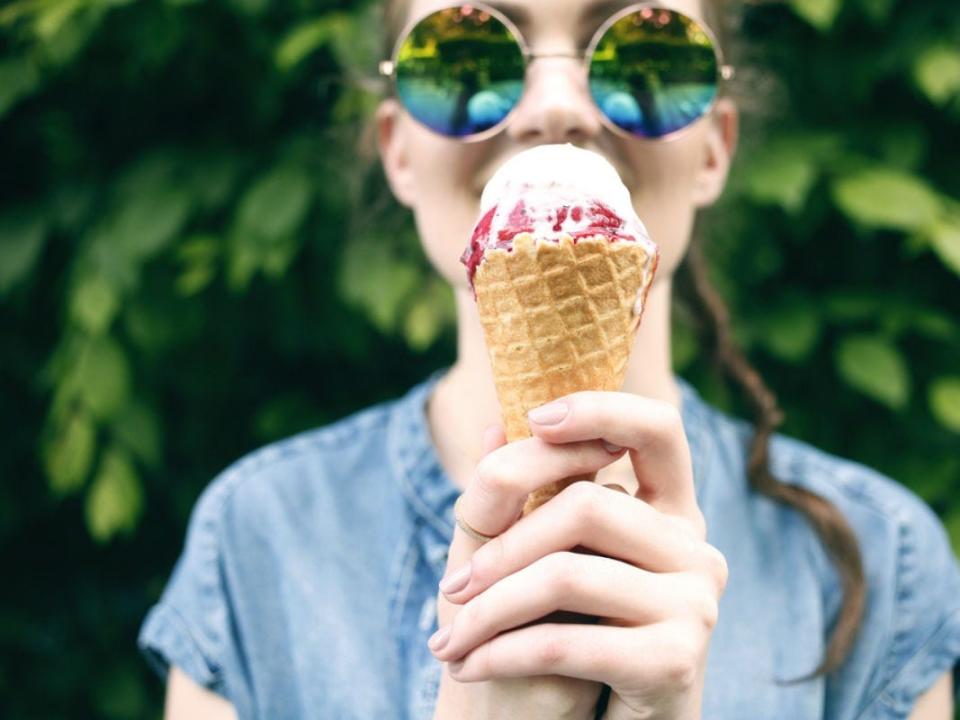 A woman holds up an ice cream cone.