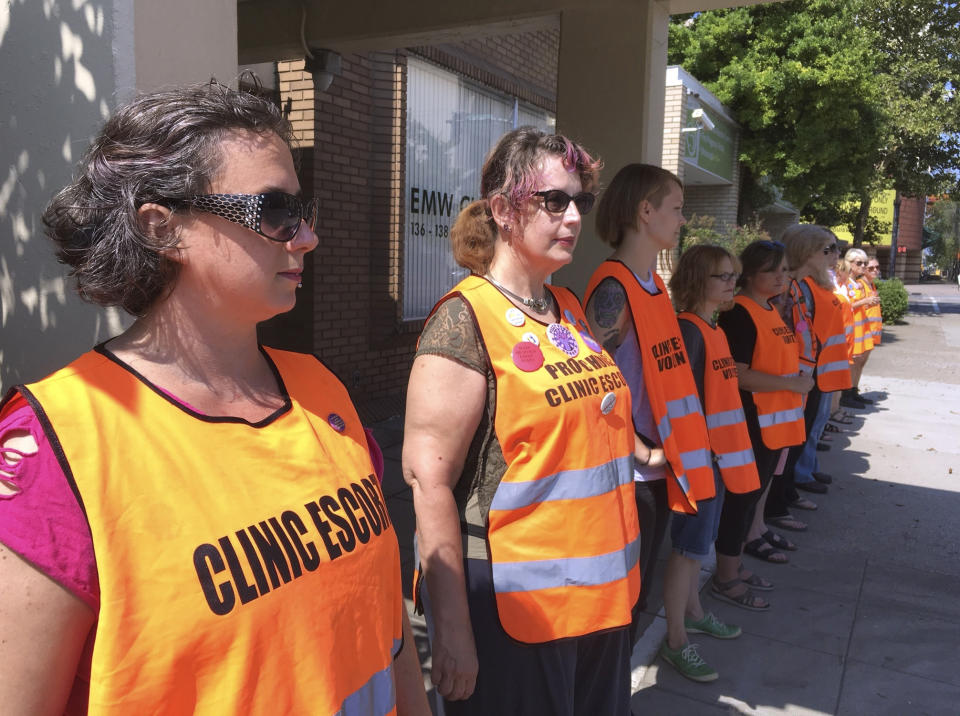 FILE - In this July 17, 2017 file photo, escort volunteers line up outside the EMW Women's Surgical Center in Louisville, Ky. A federal judge in Kentucky has cautioned lawyers to watch their language in their bitter legal feud over abortion, this time over a lawsuit challenging two new state laws aimed at putting more restrictions on the procedure. (AP Photo/Dylan Lovan, File)
