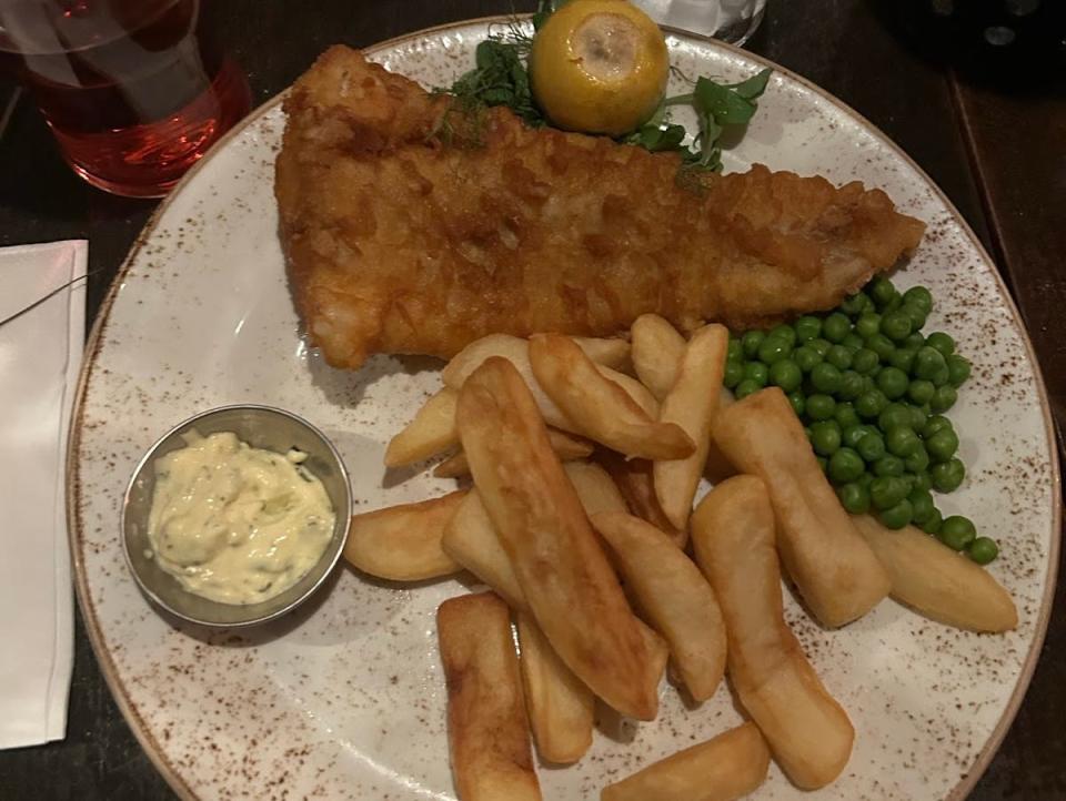 plate of fish chips and peas on a table in a restaurant in london