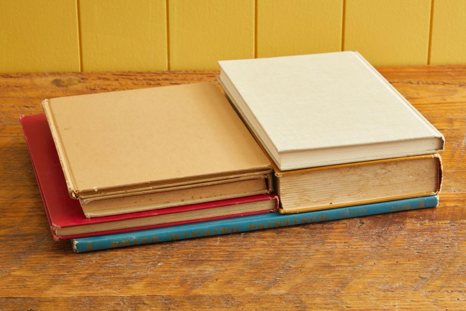 books stacked up on a table used to press flowers