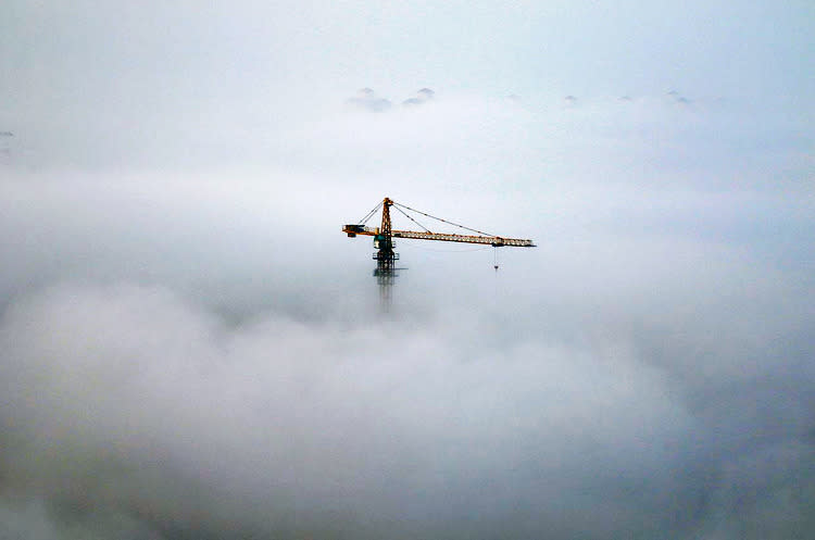 Ein Kran ragt im chinesischen Yantai aus dem Nebel heraus. (Bild: China Daily/Reuters)