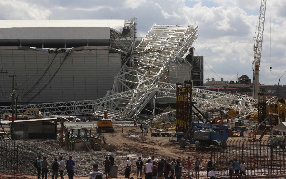 Workers stand near a crane that collapsed on the site of the Arena Sao Paulo stadium, known as "Itaquerao", which will host the opening soccer match of the 2014 World Cup, in Sao Paulo