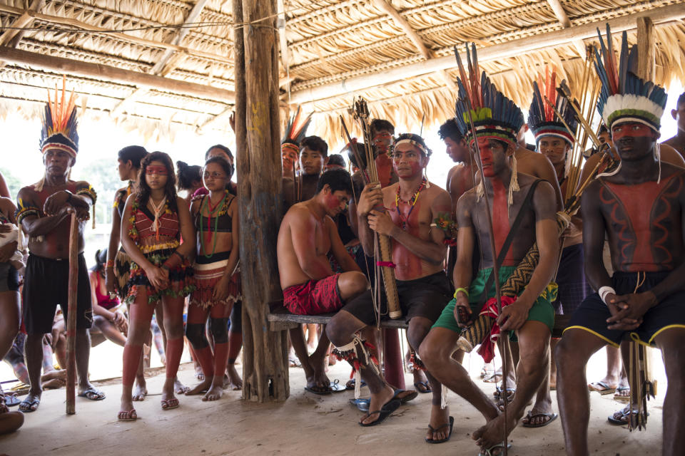 In this Sept. 3, 2019 photo, indigenous villagers listen to speakers during a meeting of Tembé tribes at the Tekohaw indigenous reserve, Para state, Brazil. Some of the men wore a type of red face paint that signified they were ready for war. Recent clashes saw the Tembe burning the trucks and equipment of illegal loggers on their territory, which is located in a Brazilian state plagued by thousands of fires burning on cleared jungle lands. (AP Photo/Rodrigo Abd)