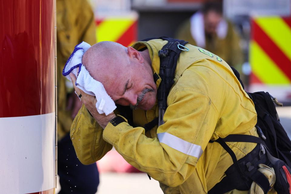 A San Bernardino County firefighter wipes his head as the Oak Fire burns near Fontana, California, on July 19, 2023.