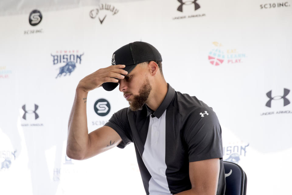 The Under Armor, Callaway, SC30, Inc., and Howard University Bison logos are visible behind Golden State Warriors guard Stephen Curry as he attends a news conference at Langston Golf Course in Washington, Monday, Aug. 19, 2019, where Curry announced that he would be sponsoring the creation of men's and women's golf teams at Howard University. (AP Photo/Andrew Harnik)