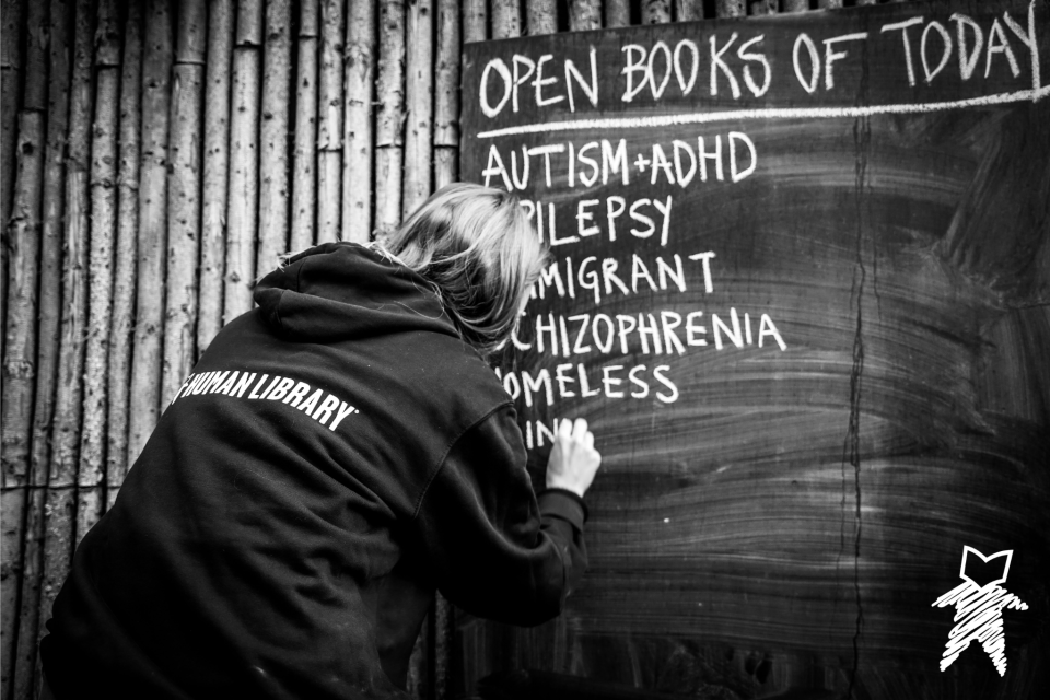 A person writing topics of Open Books from the Human Library Organization.